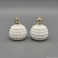 Front view of both milk glass hobnail shakers with metal tops
