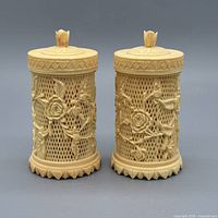 Front view of both carved ivory plastic toothpick holders with lids on