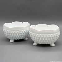 Two white milk glass diamond point footed bowls on grey background