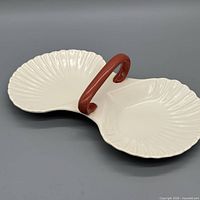 Angled top view of cream double dish with red handle