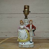Front view of porcelain table lamp with Victorian couple and brass socket