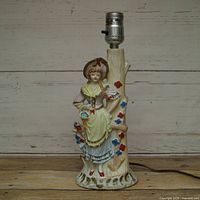 Front view of ceramic figural table lamp showing Victorian lady and floral details