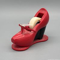 Side view of red and black shoe-shaped Scotch tape dispenser with tape roll