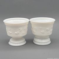 Two identical white milk glass pedestal bowls front view