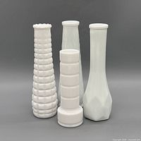 Front view of all four white milk glass vases showing textures and shapes