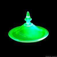 Lid glowing bright green under UV light showing uranium glass fluorescence
