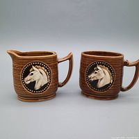 Front view of both creamer and sugar bowl showing horse motifs and overall design