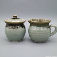 Front view of creamer and lidded sugar jar showing glaze colors and forms