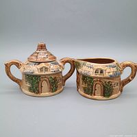 Front view of ceramic sugar bowl with lid and matching creamer pitcher