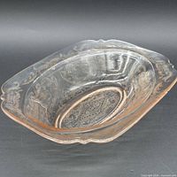 Angled side view of pink Depression glass bowl displaying flared form and pattern