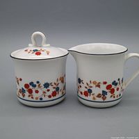 Front view of creamer and lidded sugar bowl showing pattern and form