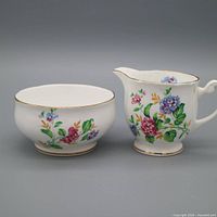 Creamer and sugar bowl front view showing floral pattern and gold trim