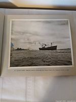 Open album showing a photograph of a cargo vessel on the St. Lawrence River