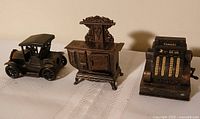 Front view of the three die-cast pencil sharpeners: car, stove, cash register