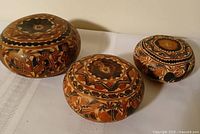 Top view of three carved gourd boxes showing detailed motifs