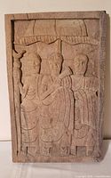 Front view of carved panel showing three figures under canopy