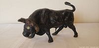 Left side view of black spelter charging bull with visible paint wear