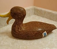 Left side view of carved wooden duck decoy showing feather detailing and blue patch
