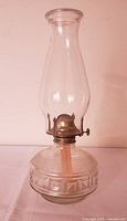 Full view of assembled clear glass oil lamp with chimney and burner