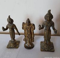 Front view of three brass Hindu deity figurines showing detail and patina