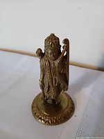 Front view of brass deity figurine with bow, arrow and crown