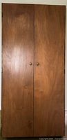 Wardrobe exterior showing two brown veneer doors with round knobs