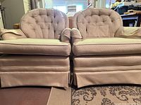 Front view of both beige tufted club chairs with cushions and pillows