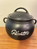 Front view of black Planters ceramic jar with lid showing logo