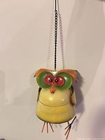 Front view of metal owl ornament hanging by chain