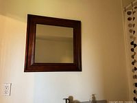 Front view of square wood frame mirror on wall