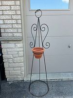 Full view of wrought iron angel plant stand with terracotta pot