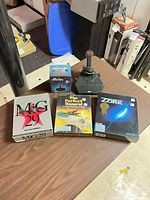 All items laid out on table: three boxed games, joystick, joystick box