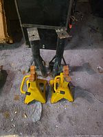 Two yellow and two black jack stands on floor