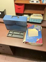 Accordion file case, desk tray and box of 100 manila folders on desk