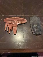 Both wooden masks side by side on flat surface