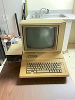 Apple II computer with CRT monitor stacked on top and Disk II drive alongside