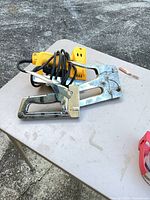 Manual chrome staple gun and yellow electric stapler on table
