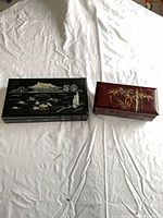 Top view showing both lacquered jewelry boxes closed: black box with scenic inlay, burgundy box with bamboo design