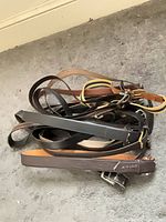 Pile of leather belts in black, brown, tan with metal buckles