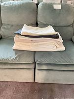 Stack of folded assorted flat sheets on sofa