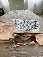 All items overview on table: sealed Maridadi placemats, peach lace linens, rope tassel tiebacks, cream doily