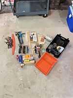 All items laid out showing variety: sprayer case, paint tray, rollers, brushes, caulk guns, sanding blocks, sheets, putty knives