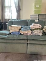 All nine folded sheet sets lined on sofa showing colour and pattern variety