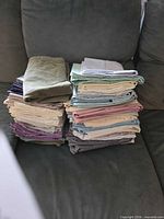 Two stacks of folded pillowcases in assorted solid colors on sofa