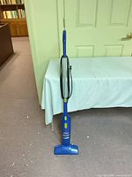 Full side view of blue Bissell Featherweight stick vacuum standing upright