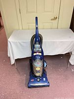 Front view of blue Bissell upright vacuum showing dirt cup and branding
