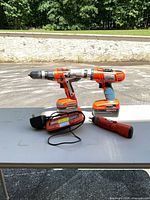 Two drills, screwdriver, charger on table