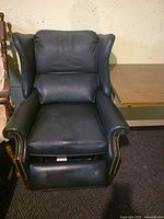 Front view of black leather wingback recliner showing overall style and nailhead trim