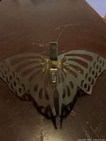 Back view of one butterfly showing cut-out wings, bronze finish and hanging hardware