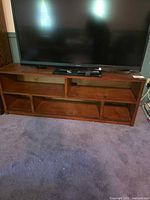 Front view of brown walnut wood TV stand with television on top